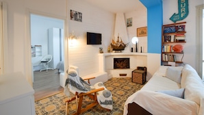 A cozy room with a bed, a chair, a fireplace, a bookshelf, and a sign that says "SURF THIS WAY". - 2 bedroom cozy apartment in Staletti (Staletti)