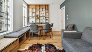 A modern living room with a built-in bench, a dining area with a wooden table and chairs, and a grey sofa. - Three Bedroom - Newly Renovated - Washer/Dryer in New York (New York)