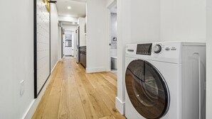 A laundry room with a washing machine, a drying rack, and a hallway leading to other rooms. - Three Bedroom - Newly Renovated - Washer/Dryer in New York (New York)