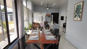 Un espace repas avec une longue table en bois, dressée pour quatre personnes, entourée de chaises noires.
