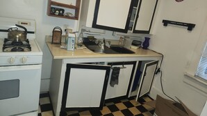 Una cocina compacta con estufa, lavamanos y un mueble pequeño.