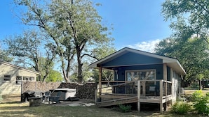 Una casa a un piano con veranda, zona barbecue e area salotto esterna coperta.