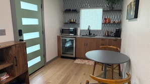 Una cucina compatta con mobili in legno, un forno a microonde e un piccolo tavolo con sedie.
