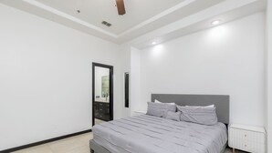 Quarto com cama, mesa de cabeceira, espelho e radiador.