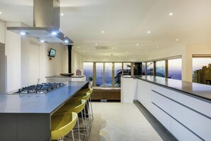 Una cocina moderna con una isla central, taburetes de bar, una estufa y un amplio ventanal con vistas.