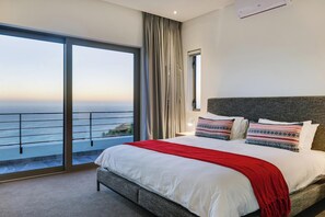 Un dormitorio con una cama grande, vistas al mar y un balcón.