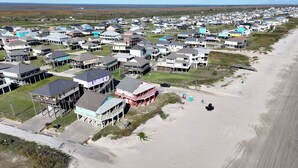 Luftaufnahme einer Küstenwohngegend mit Häusern, einem Strand und blauem Himmel.