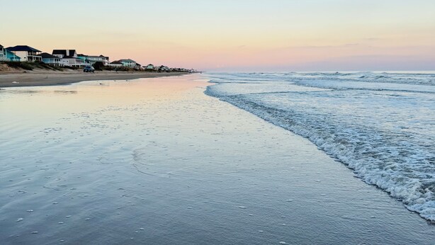 Ein Strand mit einer Reihe von Häusern entlang der Küste.