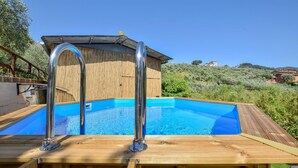 Une terrasse en bois avec une piscine, des échelles métalliques pour la piscine et une clôture en bois.
