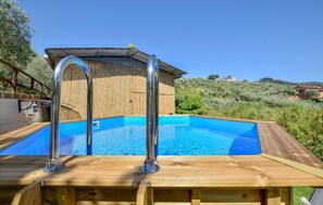 Une terrasse en bois avec une piscine, des échelles métalliques pour la piscine et une clôture en bois.