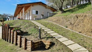 Une maison située sur une colline, avec un chemin de pierre menant à l’entrée.