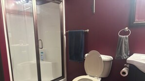Ein Badezimmer mit Duschkabine, Toilette, Waschbecken und Handtuchhalter.
