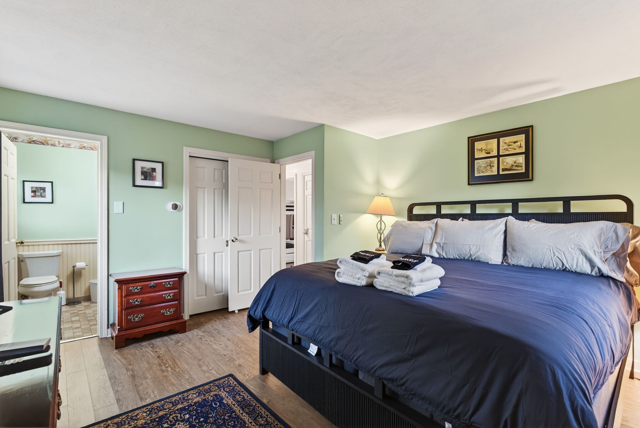 A bedroom with a bed, a dresser, a lamp, and a framed picture on the wall.