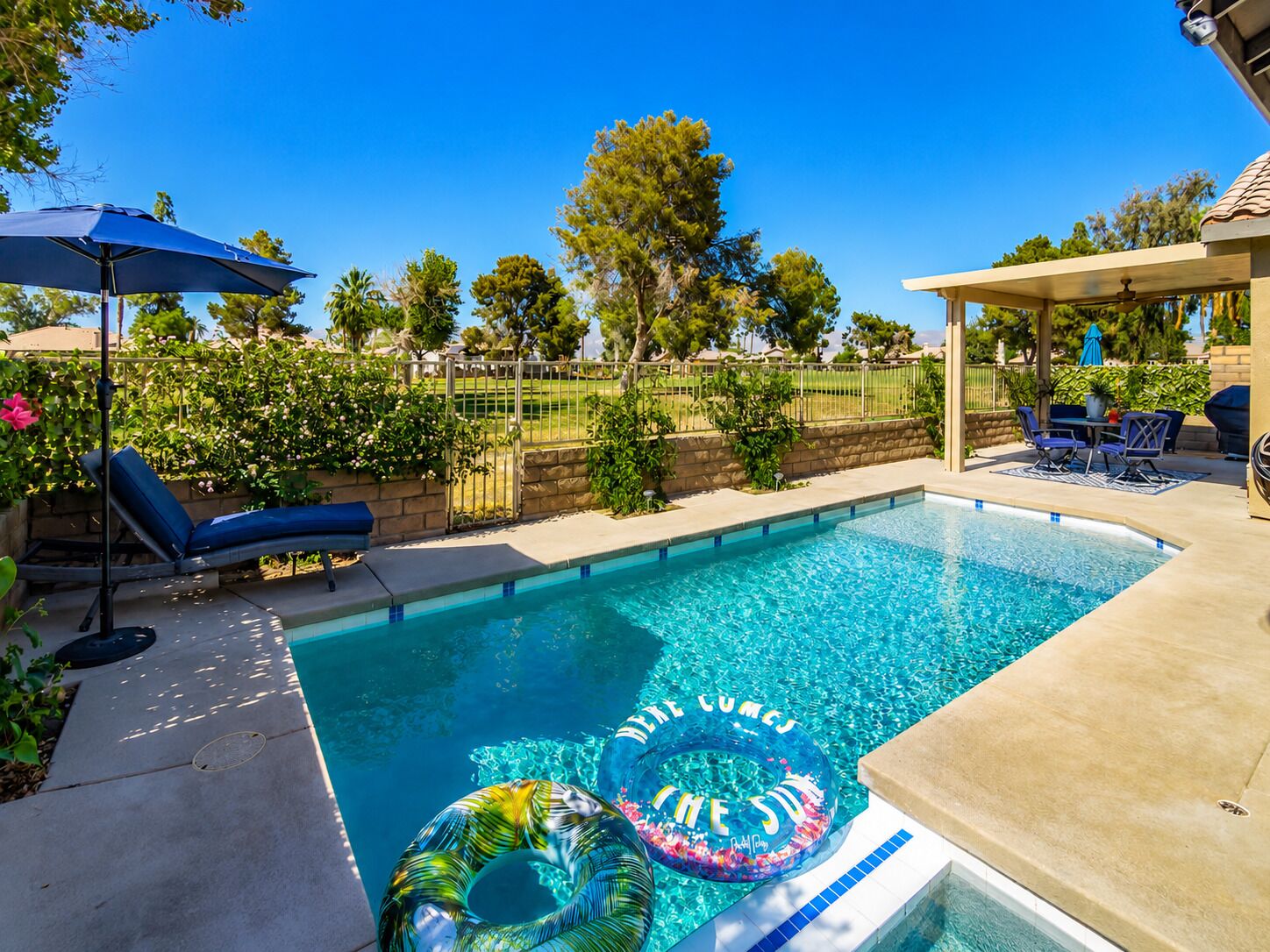 A swimming pool with lounge chairs and a covered patio area.