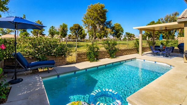 Uma piscina com espreguiçadeiras e um terraço coberto.