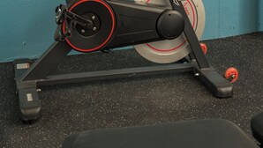 Un vélo d’appartement doté d’une selle et de poignées noires, placé devant un mur de couleur turquoise.
