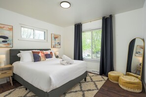 A modern bedroom with a large bed, bedside tables, a mirror, and artwork on the walls.