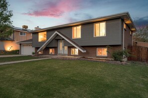 A two-story house with a garage, a sloped roof, and a well-maintained lawn.