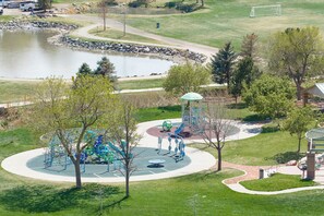 A park with a playground, a gazebo, and a pond.