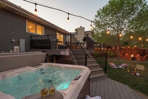 A backyard with a hot tub, outdoor seating, and a staircase leading to a deck.