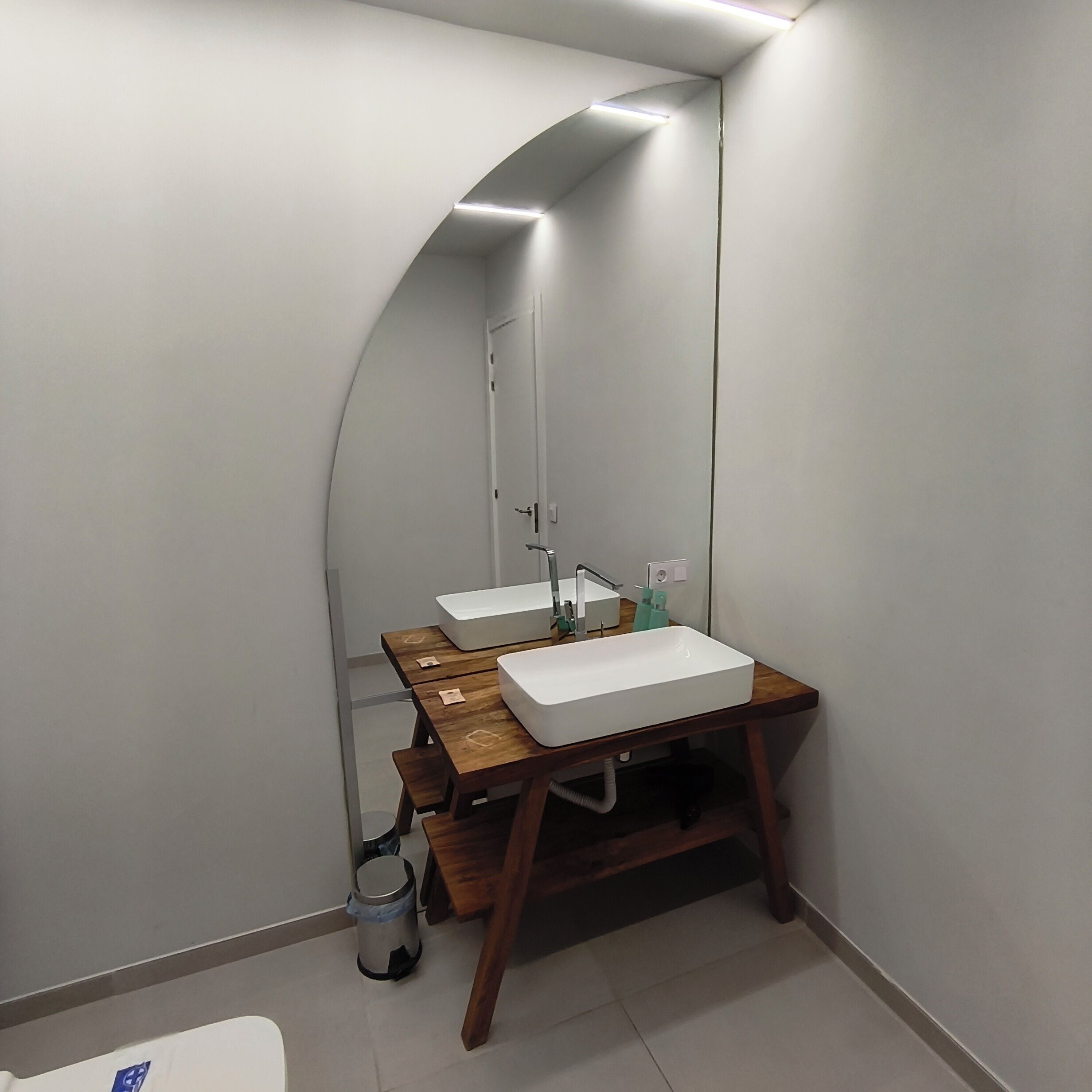 Une salle de bain moderne avec deux vasques, un meuble-lavabo en bois et un miroir.