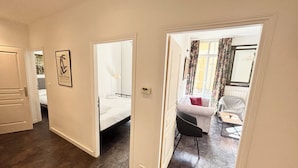 A hotel room with a bed, a chair, a small table, and a view of the outside through a window.