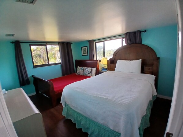 A hotel room with a single bed, a desk, and a window with curtains.