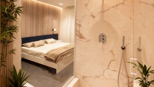 Une salle de bain moderne avec un grand miroir, une douche équipée d’un pommeau de douche à main et une baignoire.