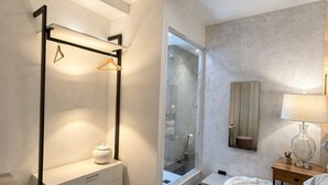 Une chambre moderne avec un dressing, un grand miroir, une table de chevet avec une lampe et un tapis moelleux.