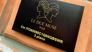 Une plaque noire avec une inscription dorée et un dessin linéaire représentant deux profils.