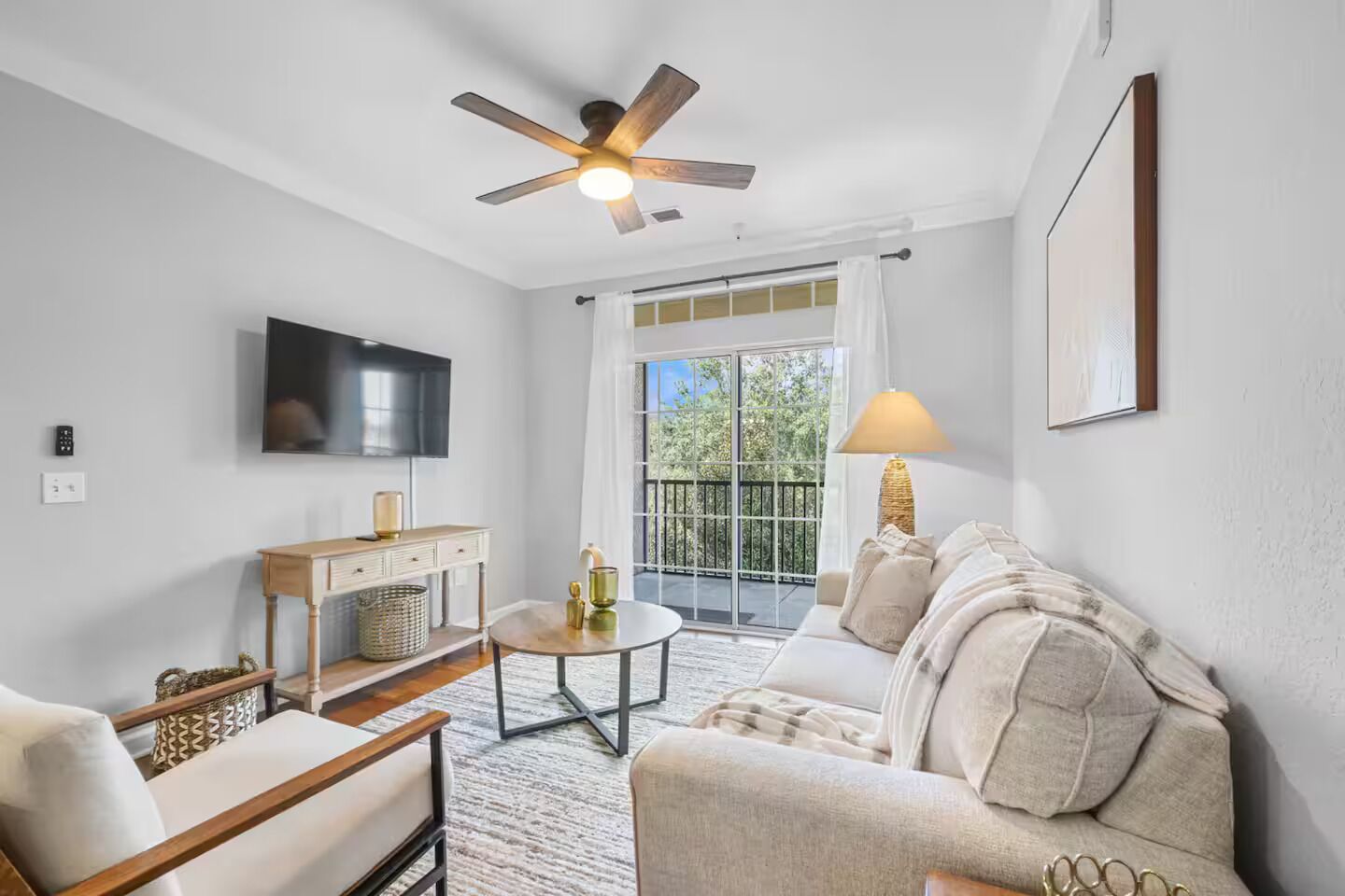 Un salon moderne doté d’un ventilateur de plafond, d’un téléviseur à écran plat, d’un canapé, d’une table basse et d’une petite table d’appoint.