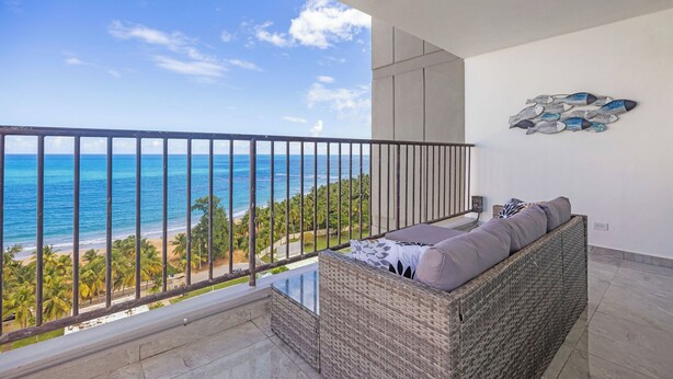 Ein Balkon mit Blick auf das Meer und Palmen.