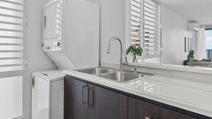 A modern kitchen with a double sink, a built-in washer and dryer, and a large window with blinds. - Designer remodeleded apt.View, Parking, location,NEW listing! (Luquillo)