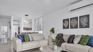 A modern living room with a beige sofa, a marble coffee table, and a potted plant. There are three framed wall art pieces above the sofa. - Designer remodeleded apt.View, Parking, location,NEW listing! (Luquillo)