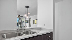 Eine moderne Küche mit zwei Edelstahl-Spülen, dunklen Holzschränken und Pendelleuchten.