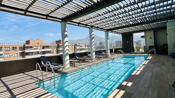Una piscina en la azotea con vistas despejadas al paisaje urbano y montañas al fondo.
