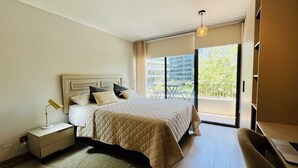 Un dormitorio moderno con una cama grande, una mesita de noche con lámpara y vistas al exterior a través de un ventanal corredero.