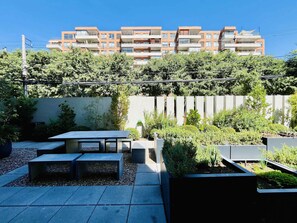A courtyard with outdoor seating, a low wall, and a building in the background. - Modern Studio Las Tranqueras - Pool, Gym & Laundry (Las Condes)