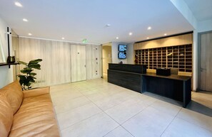 Una moderna hall d'hotel con una reception, un'area salotto e una grande pianta.