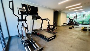Un gimnasio con máquinas de cardio, una bicicleta estática y equipo de levantamiento de pesas.