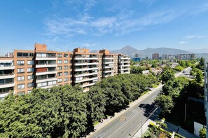 A multi-story residential building with balconies, surrounded by trees and a clear sky. - Studio Las Tranqueras - Fast Wifi, Gym & Laundry (Las Condes)