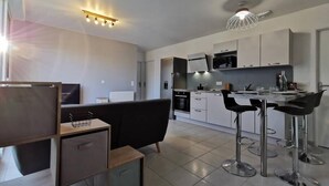 A modern kitchen with white cabinets, a microwave, and a dining area with bar stools. - House with 5 bedrooms and 3 bathrooms | 1 bed 160cm & 4 beds 120cm (Etampes sur marne)