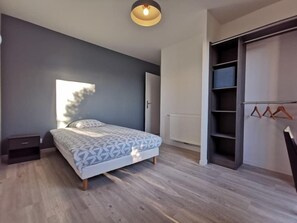 Una camera da letto moderna con un letto, un comodino, un armadio e una rastrelliera appendiabiti.