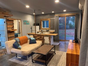 Ein modernes Wohnzimmer mit Sofa, Couchtisch und Küchenbereich mit Fenster und Schiebetüren.