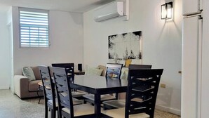A dining area with a table and chairs, a sofa, and a wall-mounted air conditioner. - Cofresi Inn - In the Heart of Cabo Rojo, PR (Cabo Rojo)