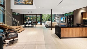 A modern interior with a kitchen island, dining area, and a staircase leading to an upper level. - Villa Strata: Modern 5 BED +POOL, minutes from The Grove, Brickell & Downtown (Miami)