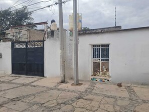 A residential area with a white building, a black gate, and a window with metal bars. - Hostal Casa Gavilan (Tecamac)