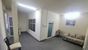 A room with a patterned floor, a sofa, a chair, a small table, a window, and a door. - Hostal Casa Gavilan (Tecamac)