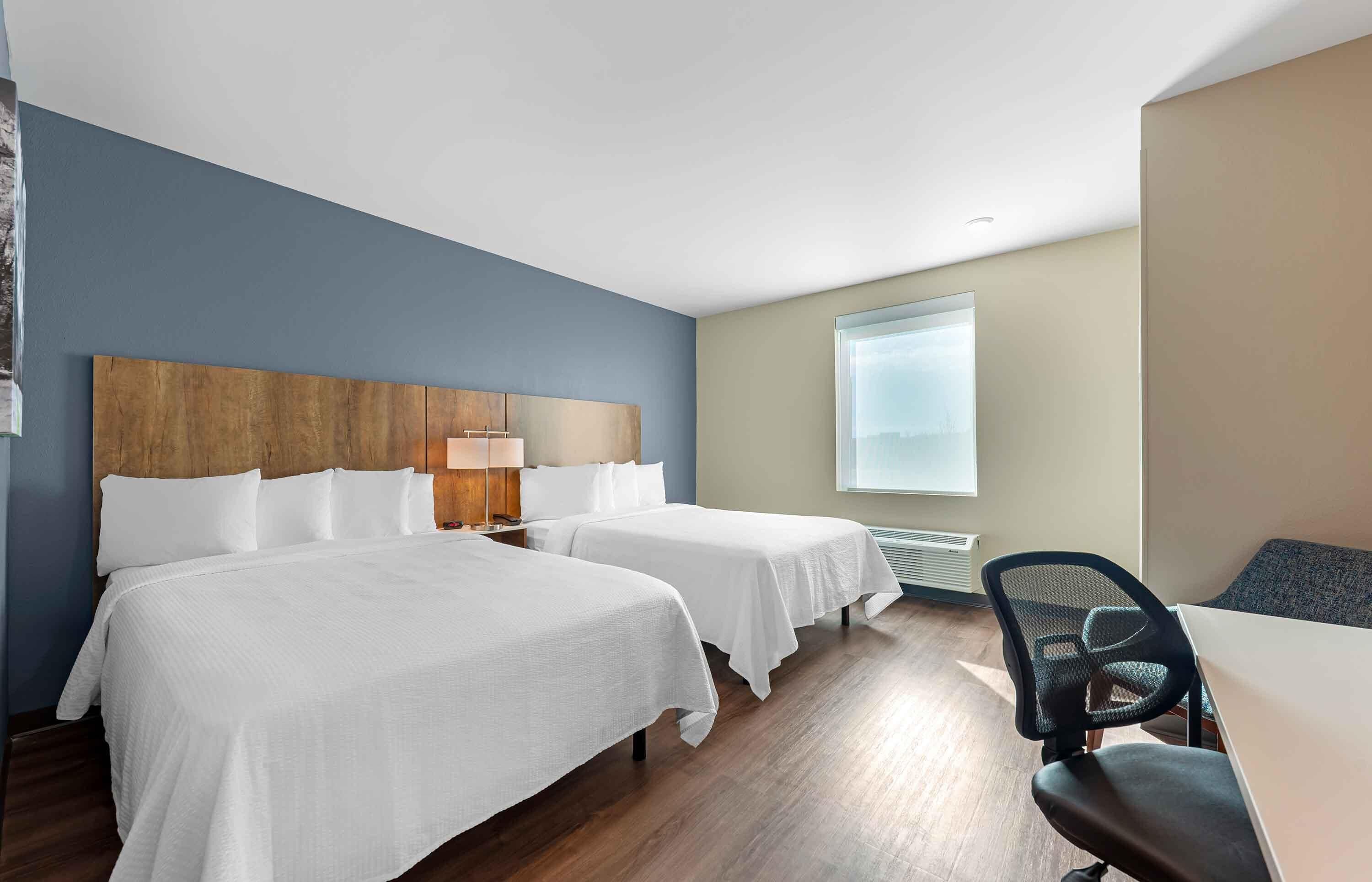 Una habitación de hotel con dos camas, un escritorio y una silla.