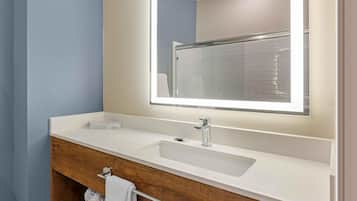 A modern bathroom with a white sink, a mirror, and a wooden vanity.